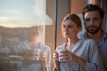 young couple enjoying evening coffee by the window