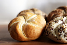 Tasty freshly baked butter kaiser roll with linseed and sunflower seeds. Top view, copy space, selective focus. Pastries on a wooden table. Blurred background. Concept of fresh pastry.