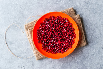 Organic Fresh Pomegranate Seeds in Red Bowl with Blue Background.