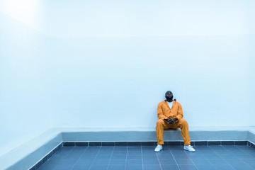 Wall Mural - african american prisoner sitting on bench in prison cell