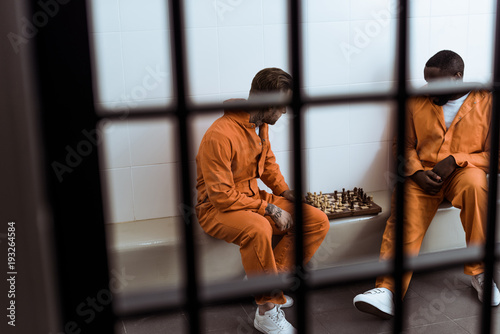 Fotografía multiethnic prisoners playing chess behind prison bars