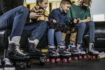  partial view of parents helping kids to wear protection before skating in skate park