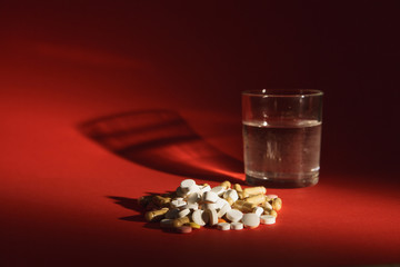 Medication white colorful tablets arranged abstract on dark red color background. Capsule vial glass of water pills design. Health treatment choice healthy lifestyle concept. Copy space advertisement.