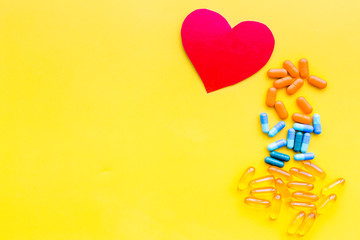 Sticker - Vitamins of drugs for heart. Color pills near heart sign on yellow background top view space for text