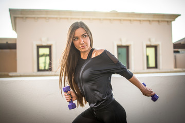 Wall Mural - Portrait of beautiful fitness girl with dumbbells outdoors.