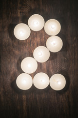 lit candles on a wooden background in the form of a number