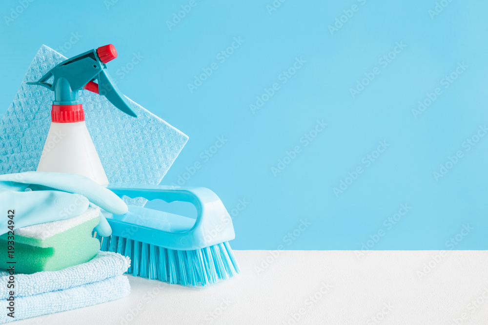 Cleaning set for different surfaces in kitchen, bathroom and other rooms. Empty place for text or logo on blue background. Cleaning service concept. Early spring regular clean up. Front view. - obrazy, fototapety, plakaty 