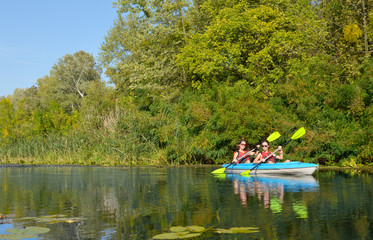 Wall Mural - Family kayaking, mother and daughter paddling in kayak on river canoe tour having fun, active autumn weekend and vacation with children, fitness concept
