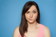 young woman looks suspiciously on a blue background
