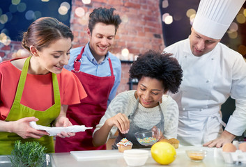 Canvas Print - happy friends and chef cook baking in kitchen