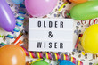 © ink drop - Party celebration background with older and wiser message on a lightbox