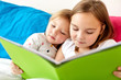 © Syda Productions - little girls or sisters reading book in bed