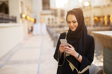 Front view of a pretty young girl smiling while looking at her phone.