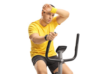 Canvas Print - Tired young man exercising on a cross-trainer machine