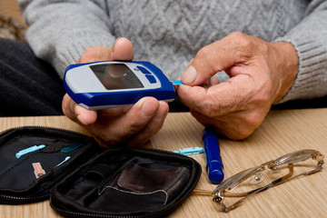 Concept diabetes in the elderly retired. Senior man with glucometer checking blood sugar level at home. Learn to use a glucometer