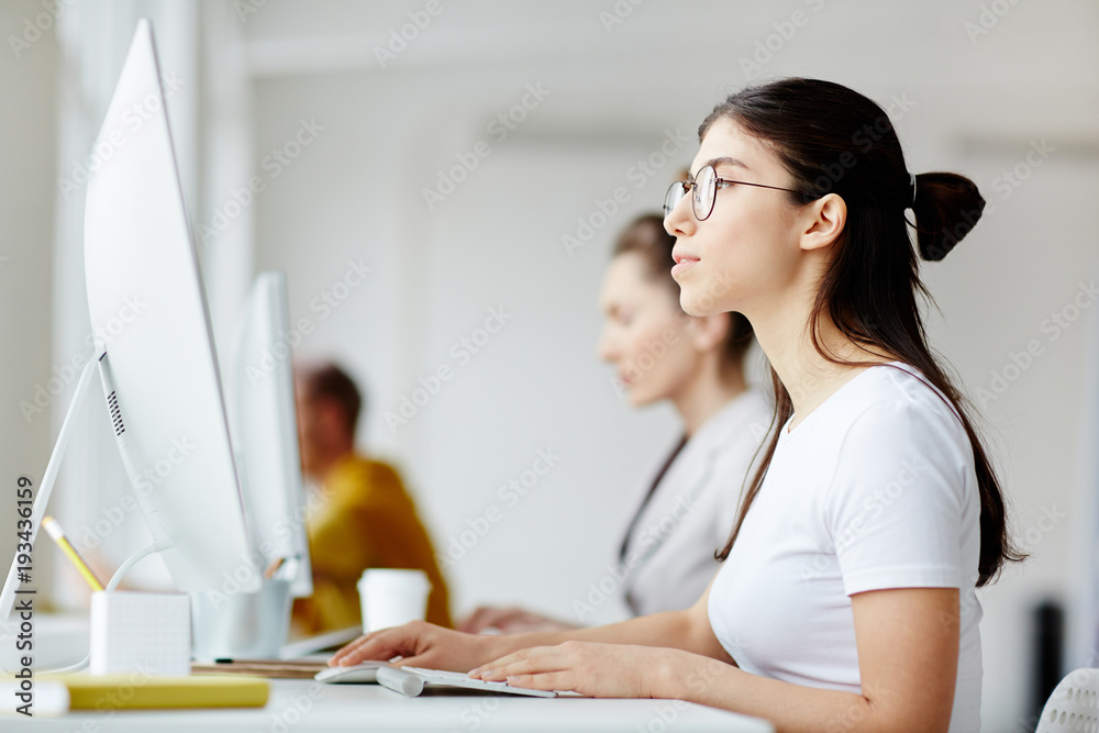 Student In Front Of A Computer Row of young students sitting by desks in front of computers and ...