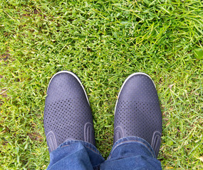 A man in jeans and summer shoes on the background of green grass . Loafers.