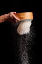 Men's Hands Are Sifting Flour Through A Sieve On Black Background