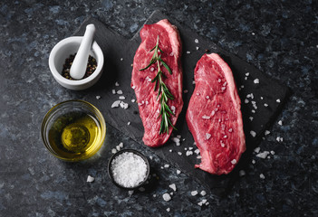 Wall Mural - Two raw picanha steaks on a cutting board with spices on a dark background