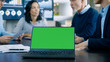 © Gorodenkoff - In the Meeting Room Laptop with Green Chroma Key Screen on the Conference Table. In the Background Business People Have Important Discussion.