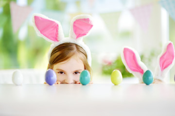 Wall Mural - Two cute little sisters wearing bunny ears playing egg hunt on Easter