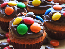 Mini Muffins With Topping From Chocolate Cream And Colored Sweets.