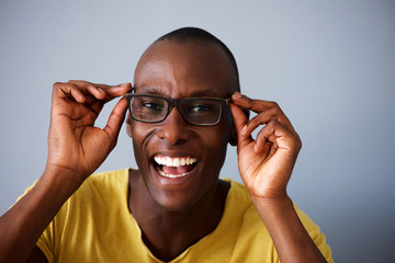 Wall Mural - Close up happy african american man smiling with glasses against gray background