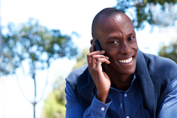 Wall Mural - Close up attractive young black man talking on mobile phone outdoors