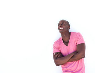 Wall Mural - happy black man laughing with arms crossed by white background