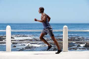 Full length healthy young african american man running by sea