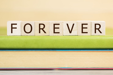 forever word built with letter cubes on green book