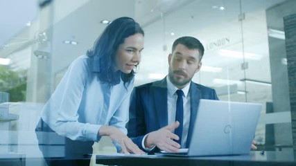 Wall Mural - Beautiful Female Manager Gives Advice to a Businessman sitting at His Desk. They Do High-Five. Working on a Laptop in Modern Office. Shot on RED EPIC-W 8K Helium Cinema Camera.