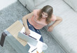 © ASDF - girl student working on laptop sitting on the carpet near the sofa.