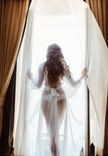 Silhouette Of Sexy Young Brunette Woman In White Lingerie In The Doorway Opening Curtains