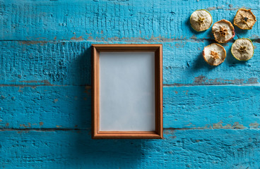 wooden photo frame on old blue wooden textured wall with empty place for text or image with slices of dried apple design