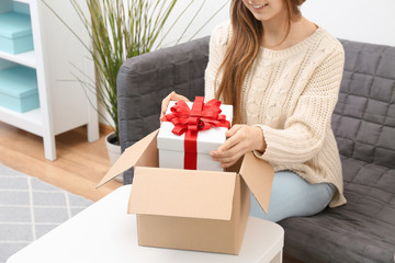 Wall Mural - Woman taking gift box out of parcel at home