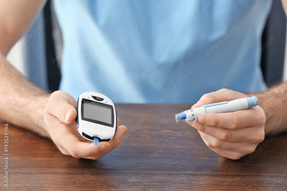 Diabetic man with digital glucometer and lancet pen, closeup