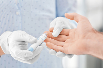 Wall Mural - Doctor taking sample of diabetic patient's blood using lancet pen, closeup