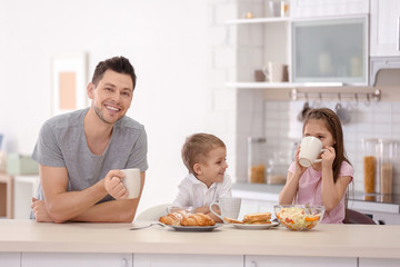 Canvas Print - Father with children having breakfast in kitchen