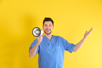 Wall Mural - Male doctor with megaphone on color background