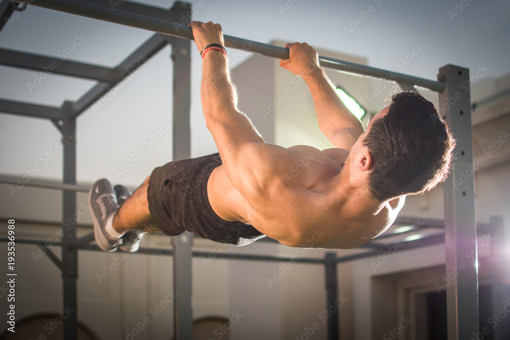 Handsome muscular man doing exercises on horizontal bar outdoors. Calisthenics workout. - obrazy, fototapety, plakaty 