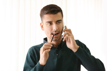 Wall Mural - Thoughtful young man talking on phone in office