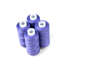 Wall Mural - Four medium purple sewing threads on a white coils on a white background. Sewing supplies