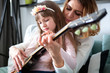 © leszekglasner - Mom with her daughter playing guitar together at home, happy family