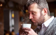 Middle age man smelling aroma of coffee in cafe