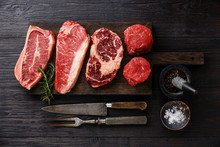 Variety Of Raw Black Angus Prime Meat Steaks Blade On Bone, Striploin, Rib Eye, Tenderloin Fillet Mignon On Wooden Board