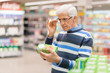 © Goran - Senior man reading food label at a grocery store