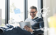 © Westend61 - Man sitting in office, using digital tablet to remote-control his smart home