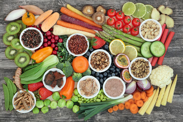 Wall Mural - Healthy super food sampler with fresh vegetables, fruit and herbal medicine, in porcelain dishes and loose, top view on rustic background. Health food concept high in antioxidants & anthocyanins.