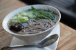 Soba noodles with soup on wood background